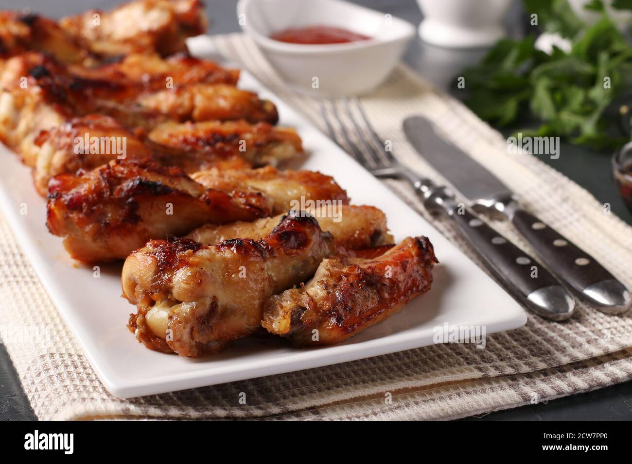Fried chicken wings on a white plate served with tomato sauce, close-up, horizontal format Stock Photo