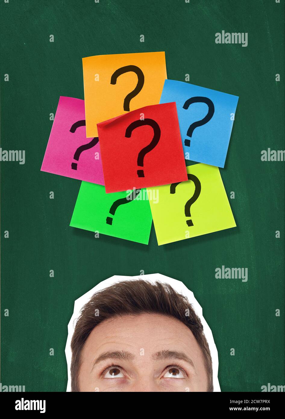 Man looking at adhesive notes with question marks on blackboard Stock Photo
