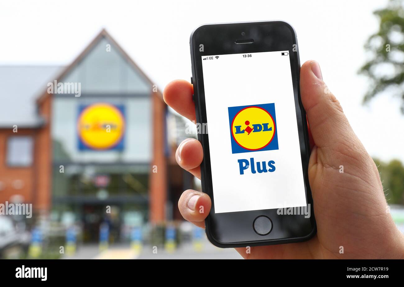 A man using the Lidl Plus App on his phone outside of a Lidi Store in the UK Stock Photo