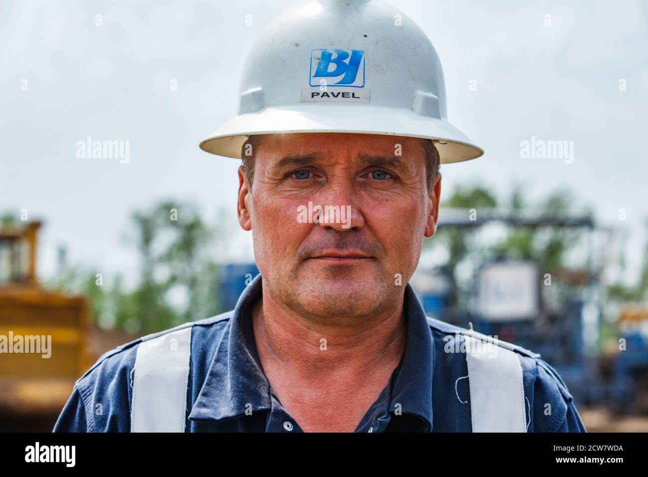 Oil deposit. Portrait of serious posing oil worker. Baker Hughes