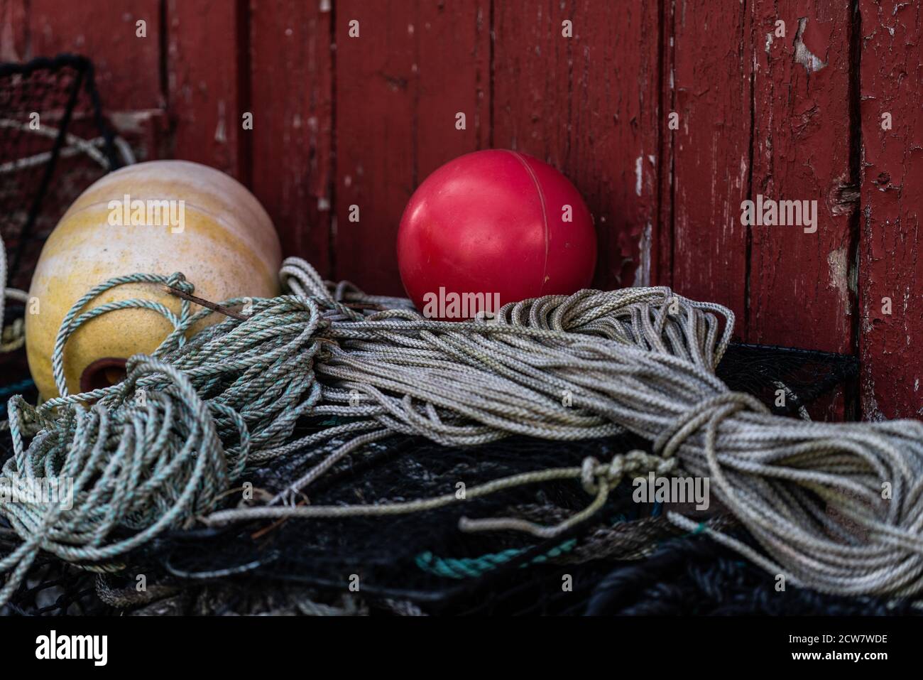 Crab and lobster gear, buoys and ropes against an old red wall where the paint is cracking Stock Photo