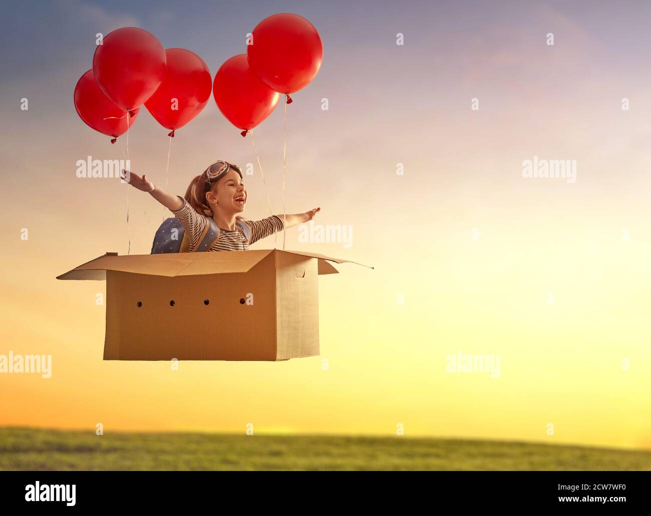 Dreams of travel! Child is flying in cardboard box with air balloons