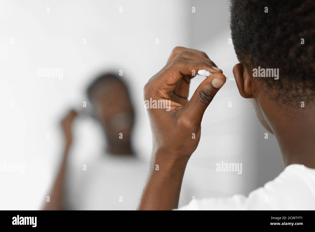 Black Man Cleaning Ears Using Cotton Swab Standing In Bathroom Stock