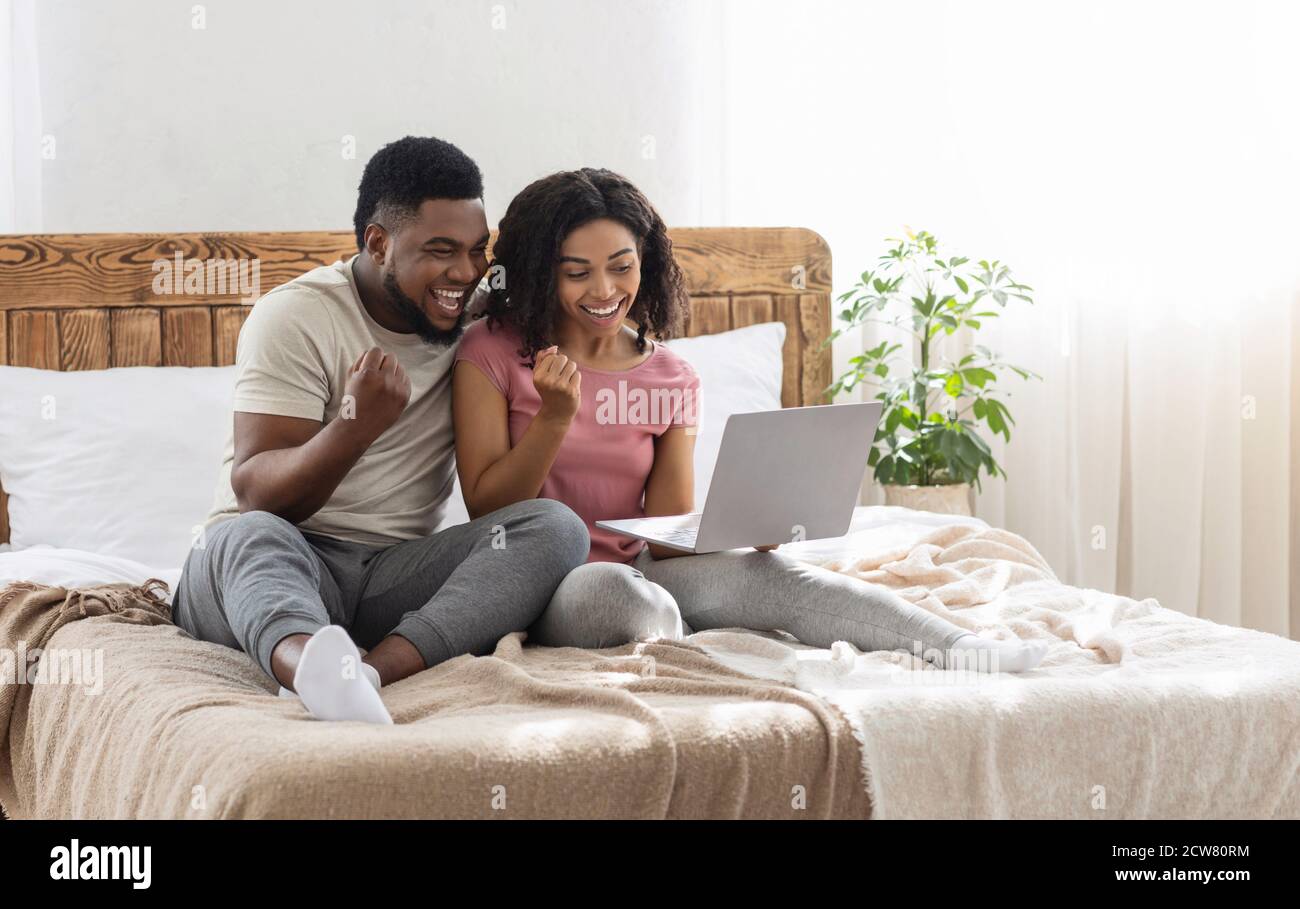 Emotional african american couple looking at laptop screen and ...