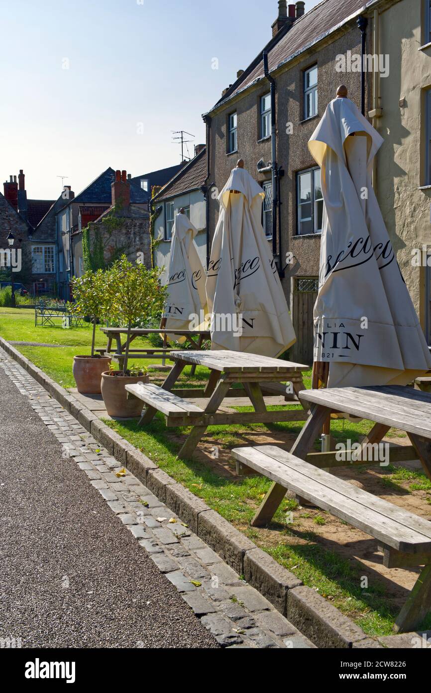 Folded umbrella parasols and picnic table benches on Wells Cathedral Green Stock Photo