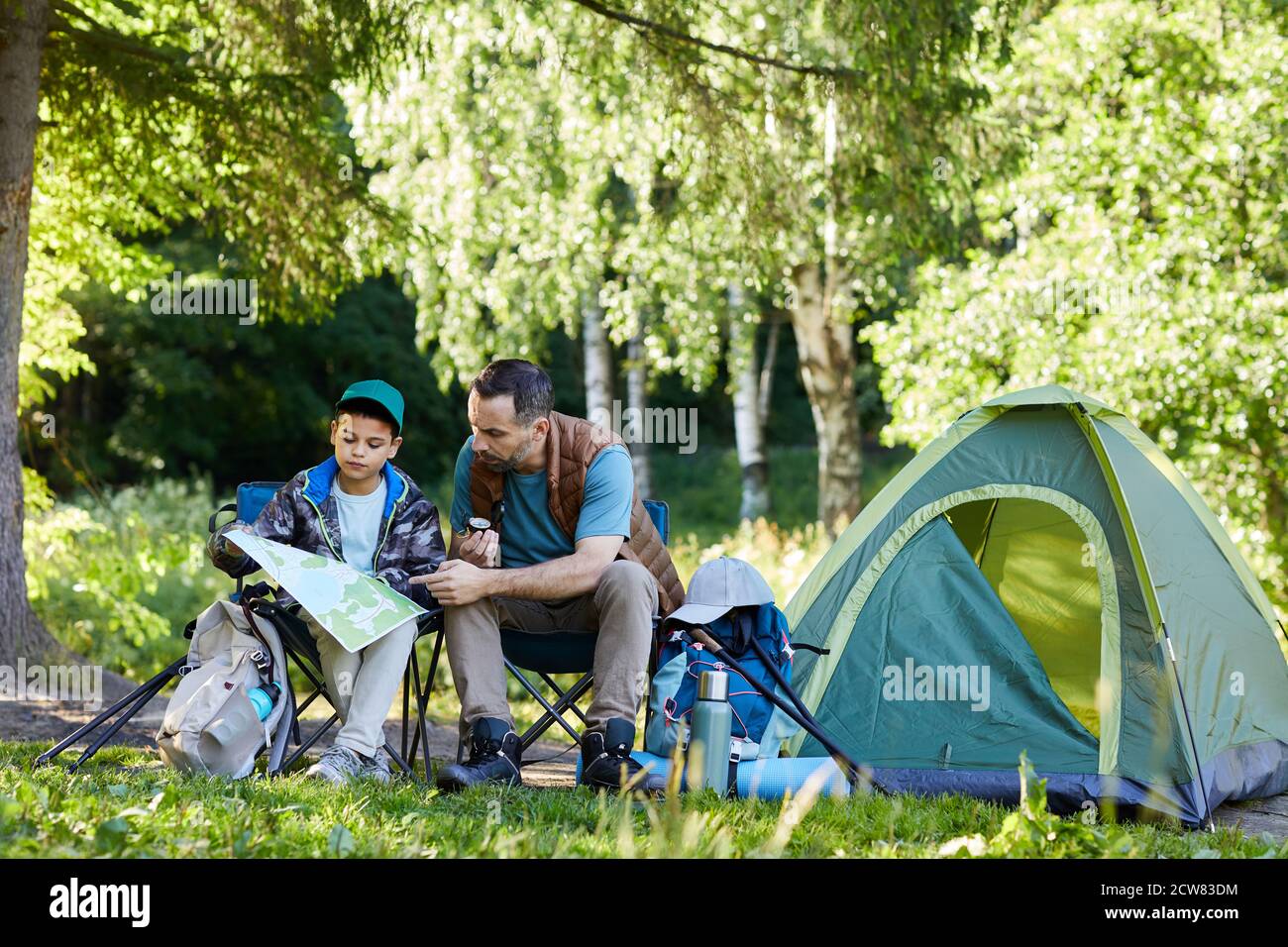Full length portrait of loving father and son looking at map while ...