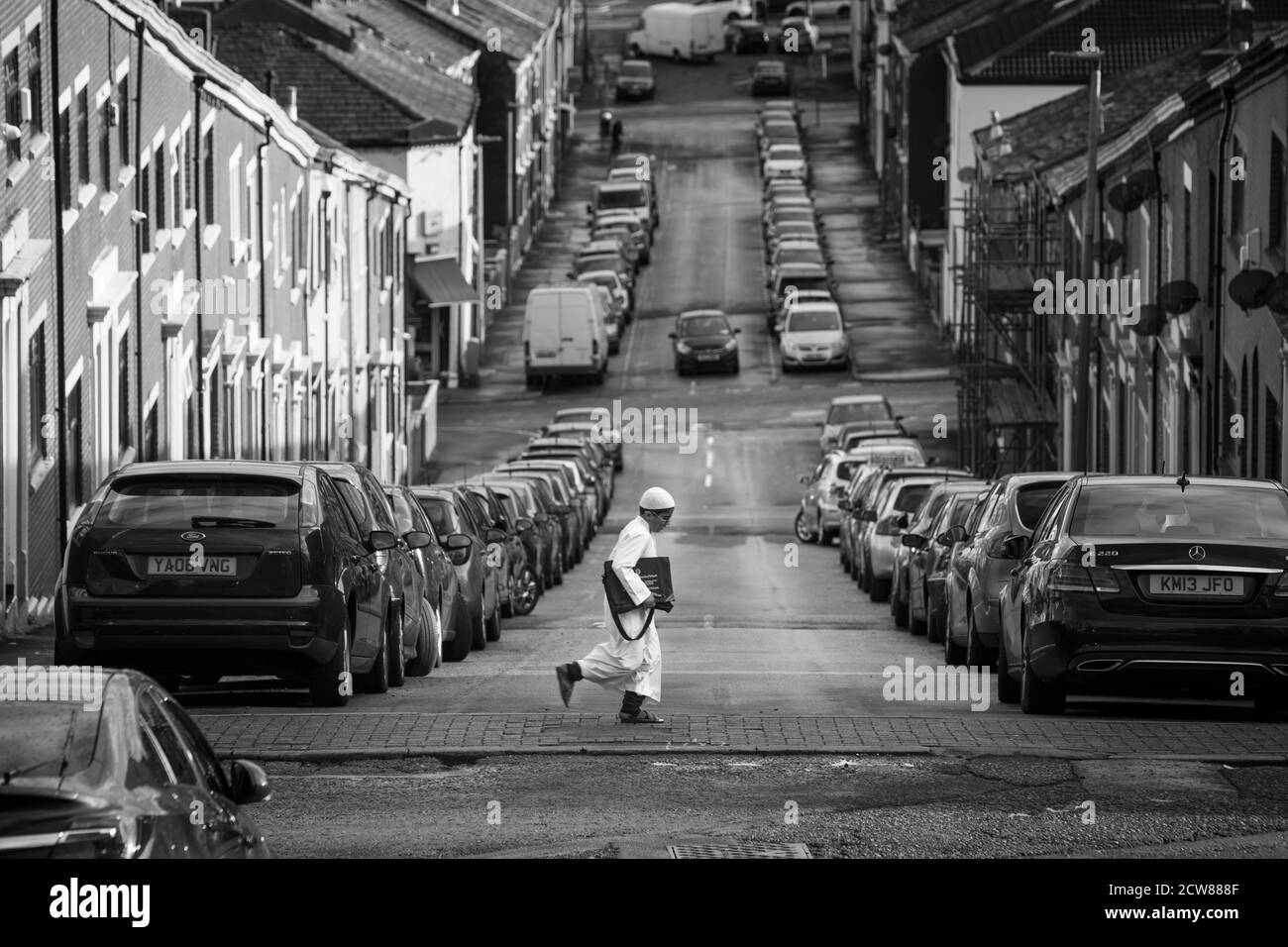 A young boy walking  across Oswald Street to the Madrasah at the Masjid E Tauheed Mosque  which lay within the Shear Brow and Corporation Park ward of Blackburn 2020. The area alongside a number of other areas in the North West and West Yorkhire have been place under additional government restriction in order to suppress the incidence and transmission  of covid 19. The Mosque reopend to its community on the 1st Spetember, 2020, under government covid 19 guidlines. During the Lockdown members of the mosque organised for food parcels to be delivered  to all communities in need within the Blackbu Stock Photo