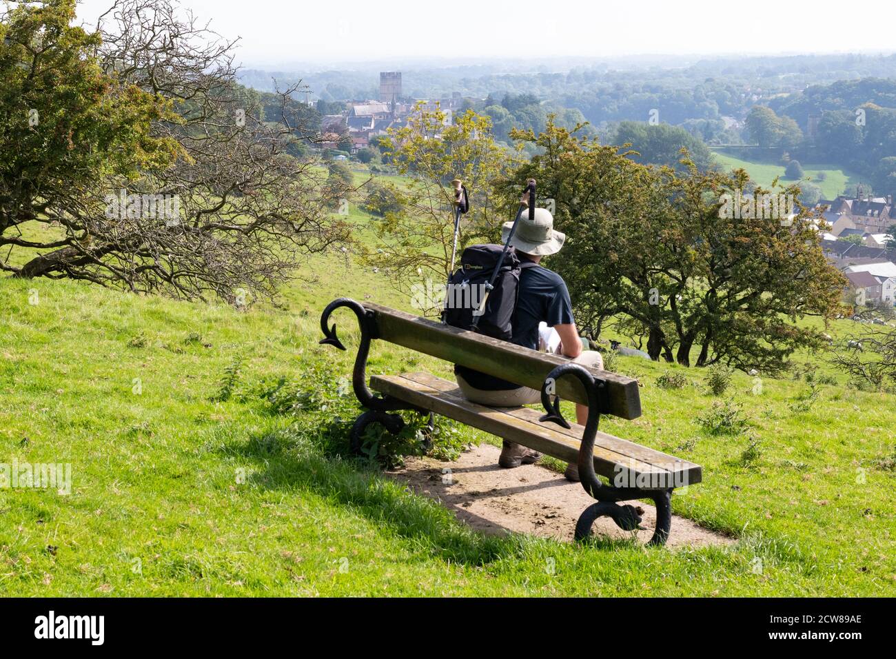 Coast to Coast walker resting on a bench with distant views of Richmond, North Yorkshire on his approach to the town, England, UK Stock Photo