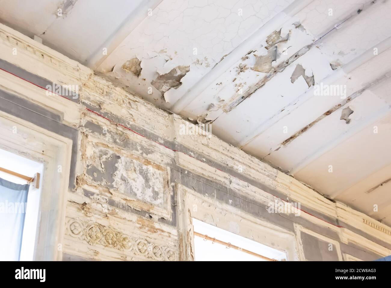Old room with window peeling plaster in the corners, walls and ceiling
