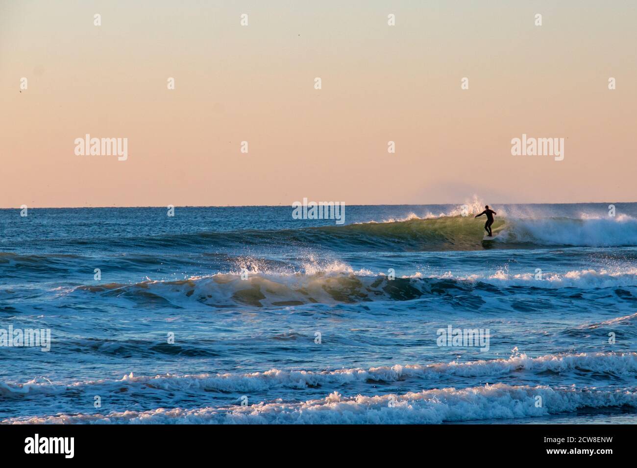 Surfer enjoying a sunset surf in California Stock Photo