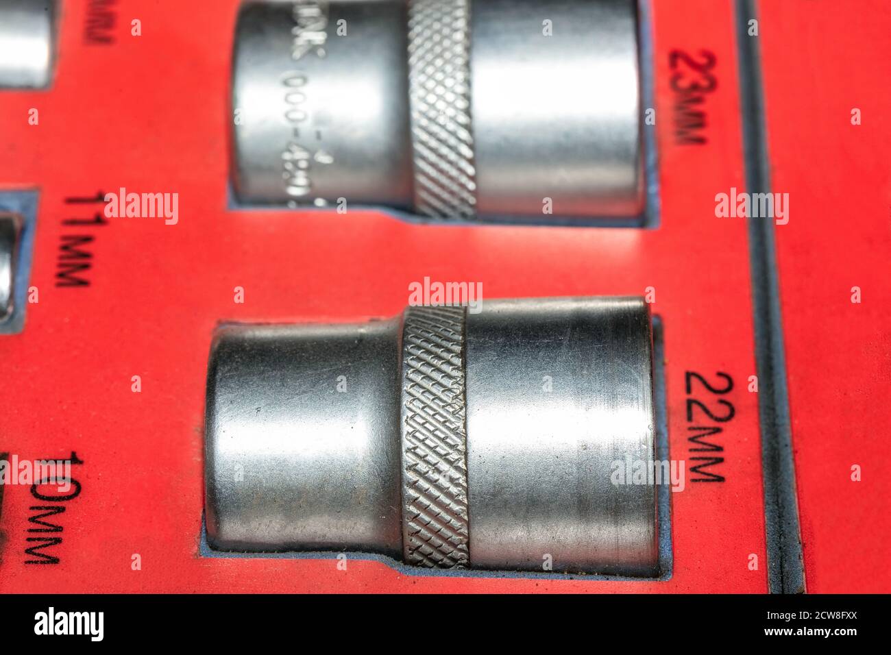 Close up shot of 22mm size metal wrench head in a set of wrench heads collection on red old worn out background. Car repair shop. Stock Photo