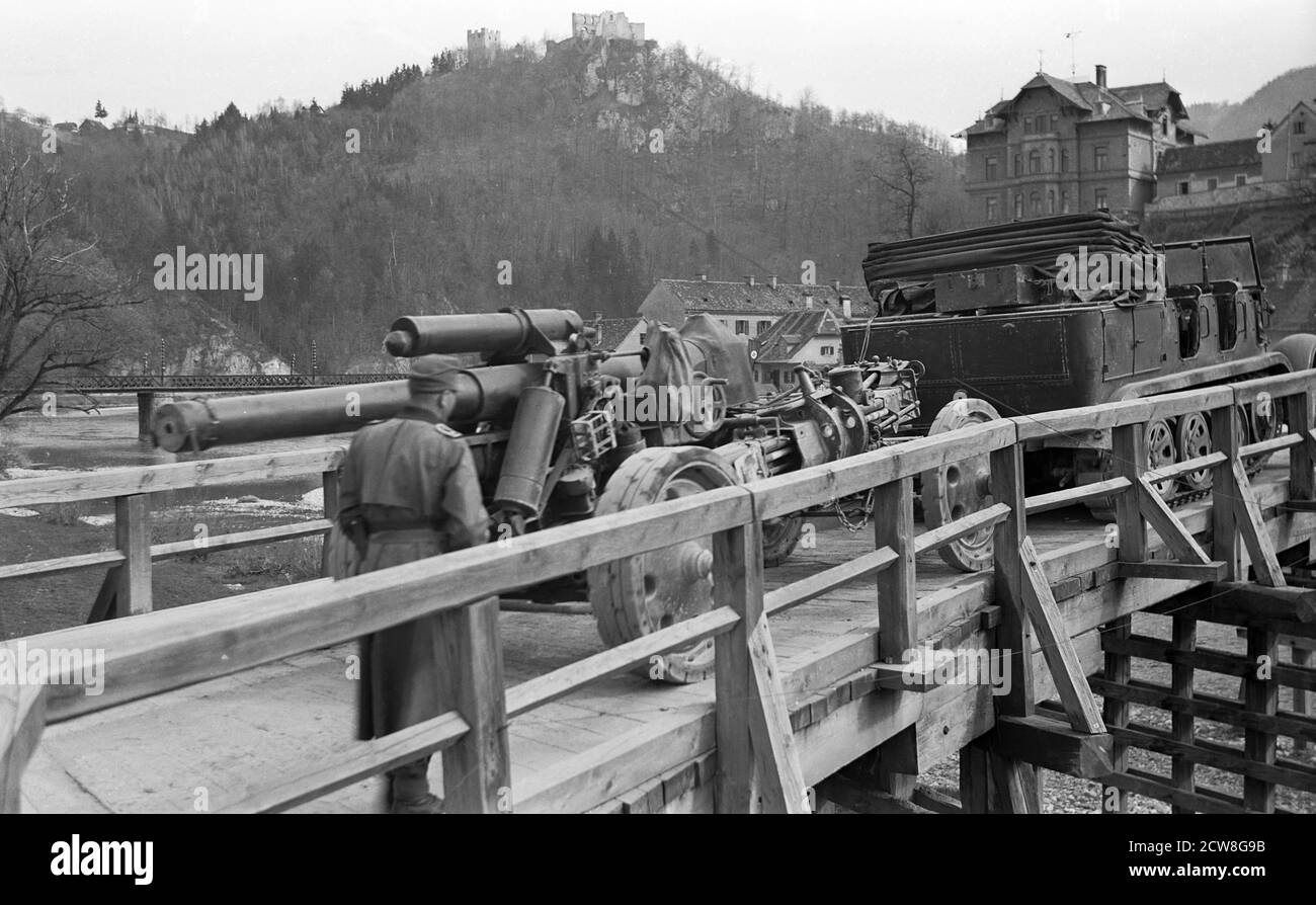 Uebergang über die Savinja in Celje (April 1941): eine schwere Feldhaubitze sFH 18, gezogen von einem Kettenfahrzeug ('Zugkraftwagen') auf einer von den Pionieren errichteten Brücke, im Hintergrund die Burg Cilli  -  German troops crossing the Savinja river in Celje 1941 Stock Photo