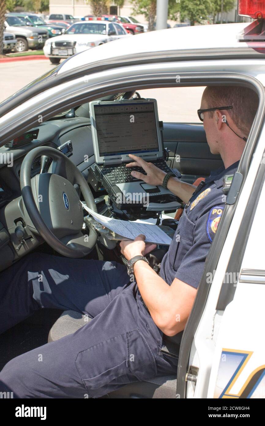 Round Rock, Texas:  July 20, 2008: Routine police work during the summertime work day in a the north Austin suburb. Officer uses his Panasonic Touchbook computer to write a report from his car. ©Bob Daemmrich Stock Photo
