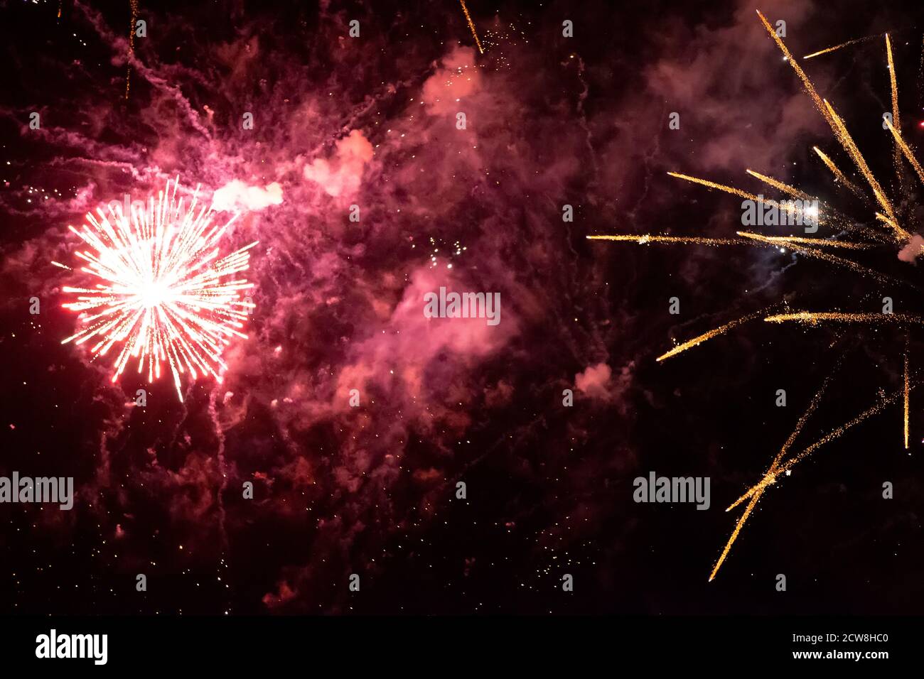 Gold rays of fireworks in red smoke on a black background. Festive background. Stock Photo
