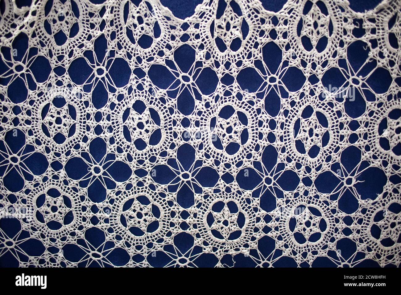 Crocheted openwork napkin on a blue background. Stock Photo