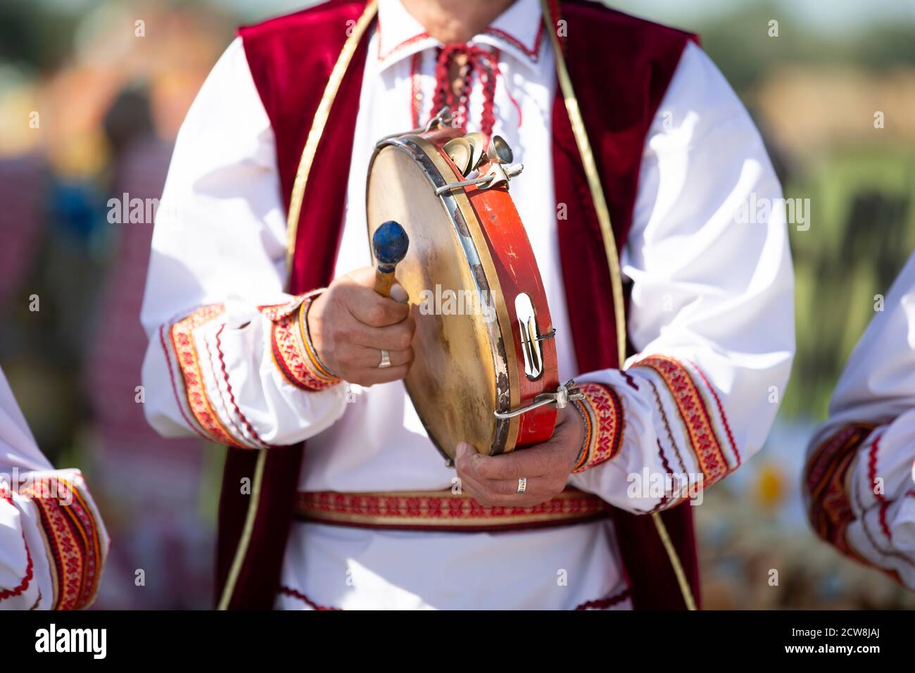 A musician in embroidery plays an ethnic drum. Stock Photo