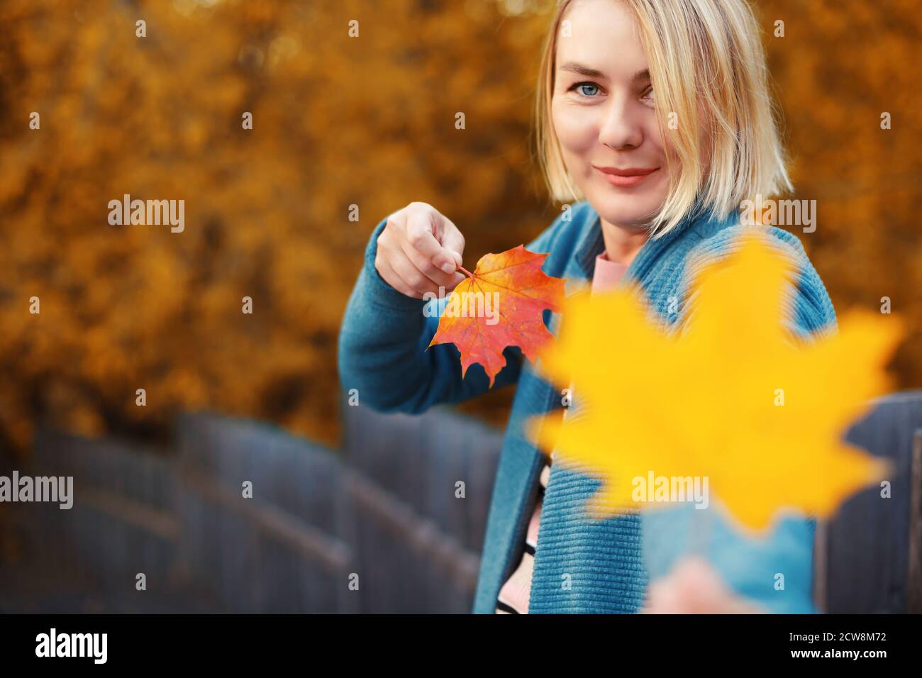 Happy smiling blonde female holding maple leaves in both hands. Woman ...