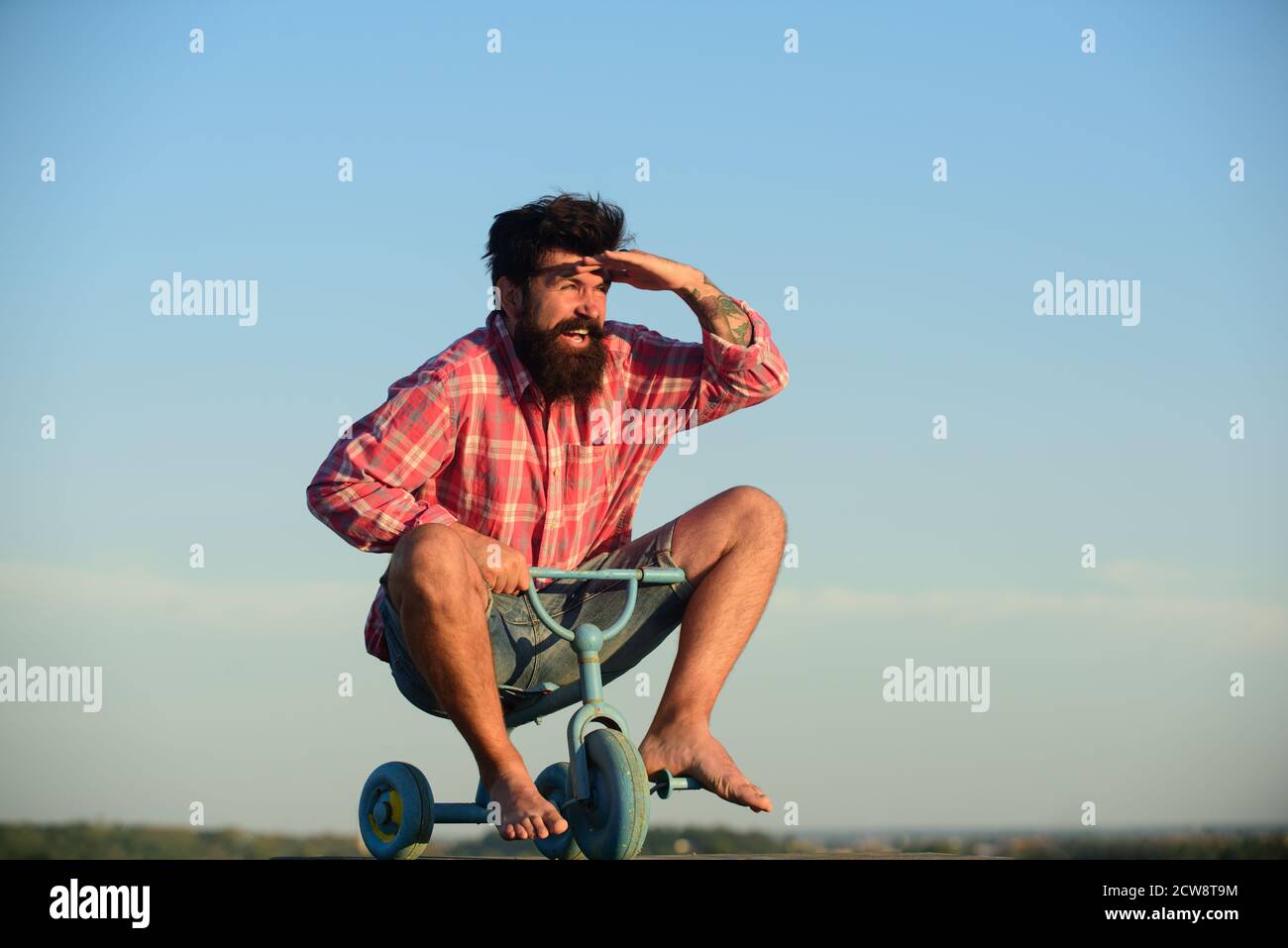 Crazy man riding a small bicycle. Funny man on a childrens bike. Stock Photo