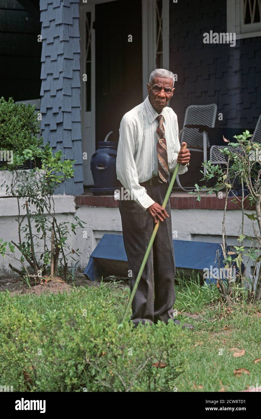 AFRICAN AMERICAN GARDENER CLEARING LEAVES FROM GARDEN, SAVANNAH, GEORGIA, USA, 1980s Stock Photo