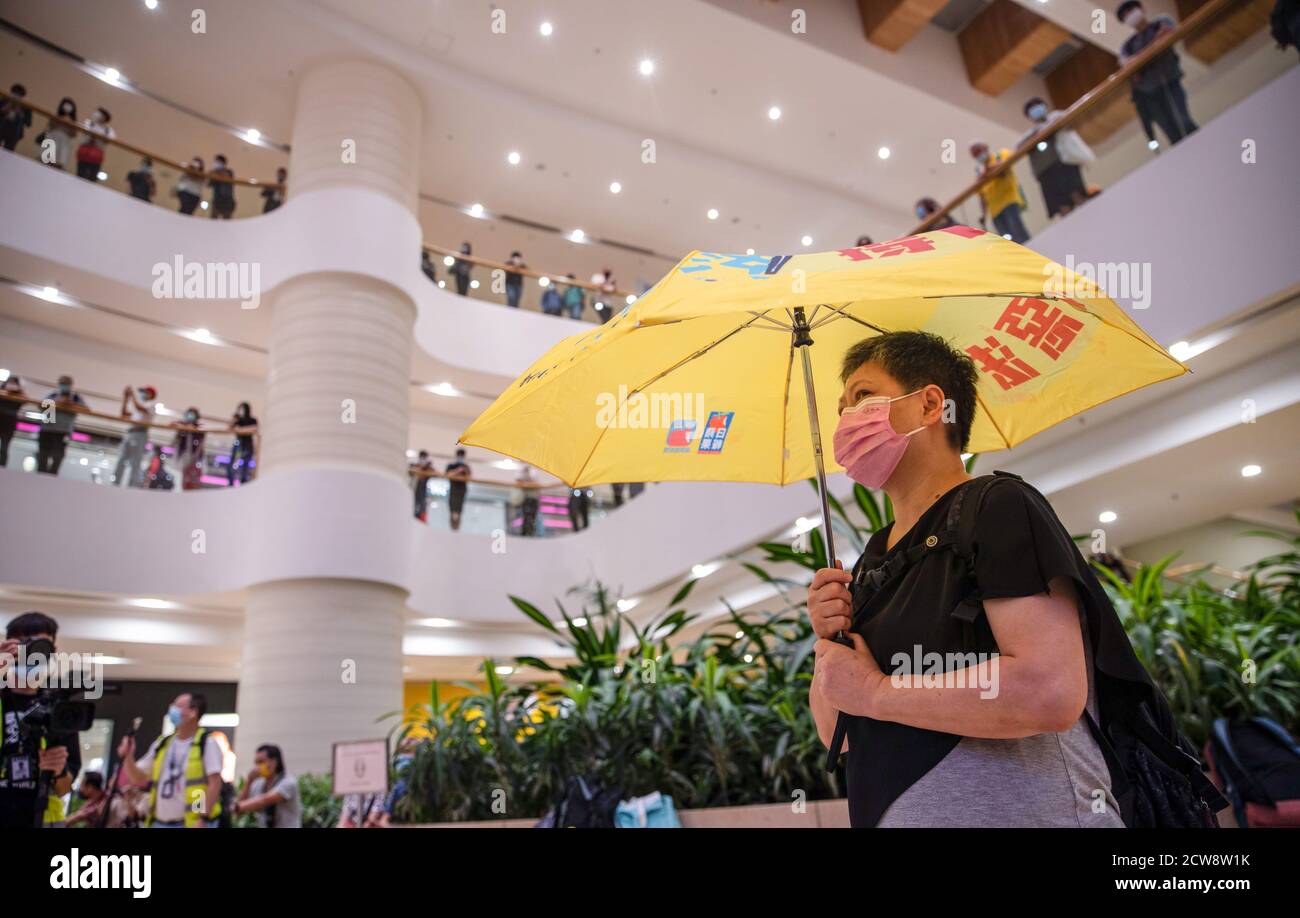 A protester wearing a facemask is seen holding a democracy umbrella during the protest to commemorate the 6th anniversary of Umbrella movement.Dozens of pro-democracy protesters gathered at the Pacific Place shopping mall in Hong Kong to mark the 6th anniversary of Umbrella movement where Hong Kongers took to the street and occupied the major roads in the city to demand for universal suffrage. Stock Photo