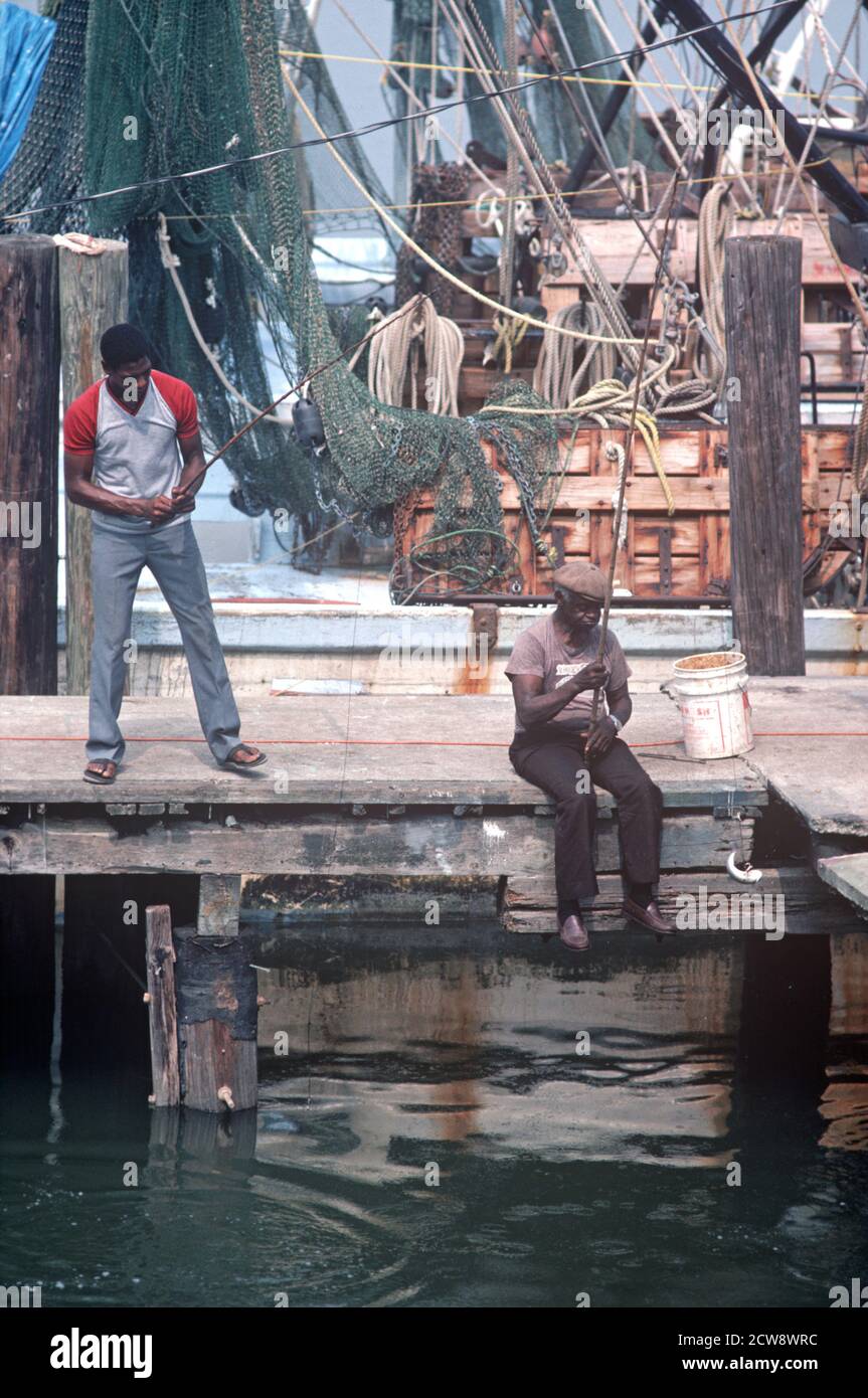 AFRICAN AMERICAN FISHERMAN AND SHRIMP FISHING BOATS ON SAVANNAH RIVER WATERFRONT, GEORGIA, USA, 1980s Stock Photo