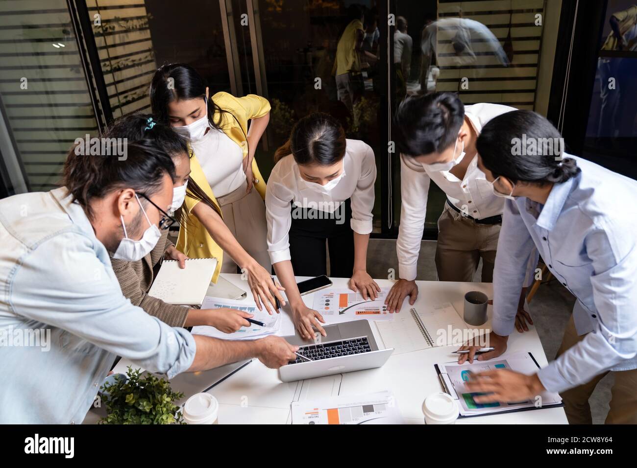 Work late concept of Interracial asian business team brainstorm idea at office meeting room at night. They wear face mask reduce risk to infection of Stock Photo
