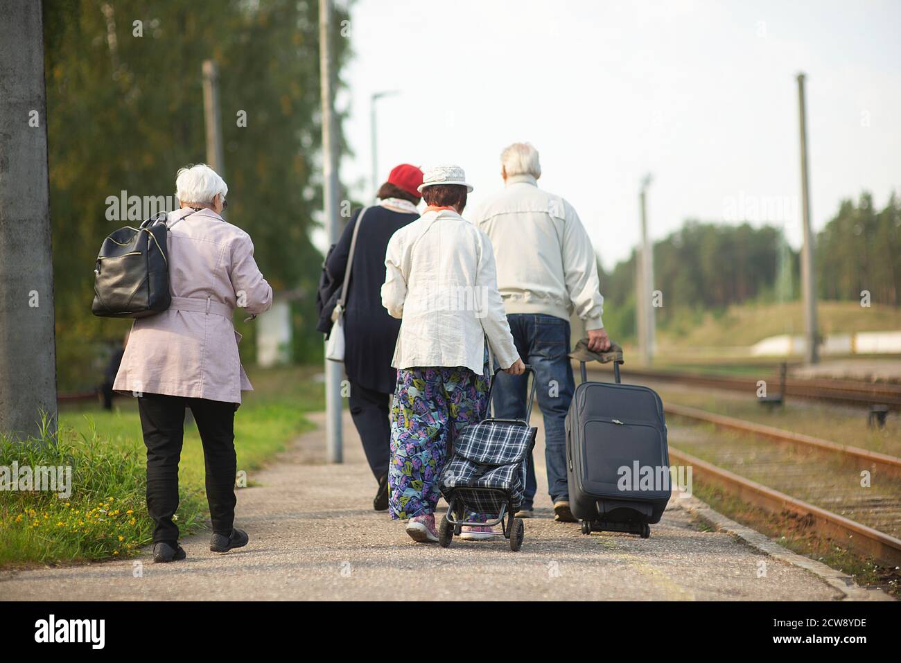 rear view of a group of seniors elderly old people with luggage waiting for a train to travel Stock Photo