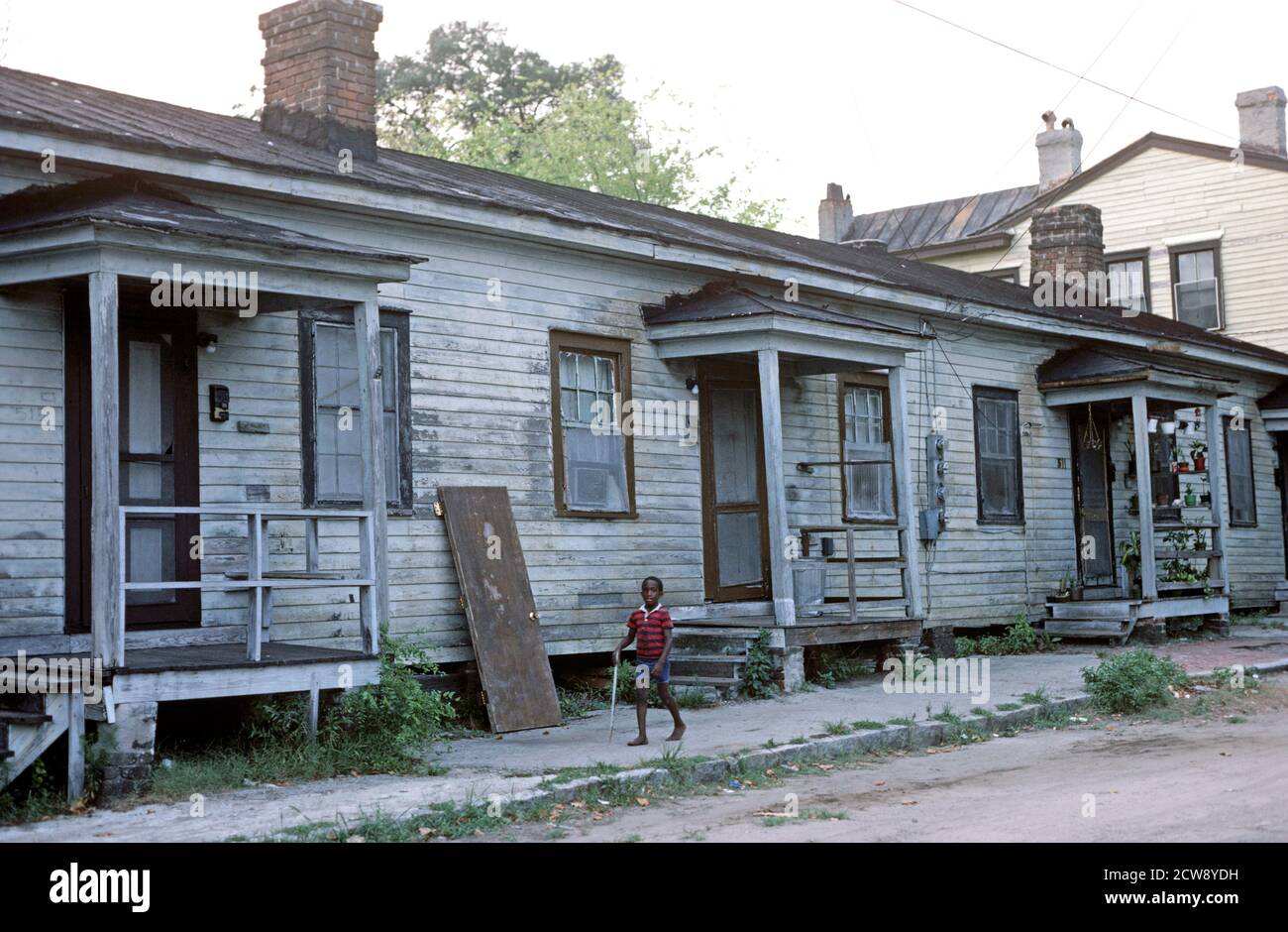 AFRICAN AMERICAN CHILD IN FRONT OF WOODEN CLAPBOARD HOUSES IN DOWNTOWN SAVANNAH, GEORGIA, USA, 1980s Stock Photo