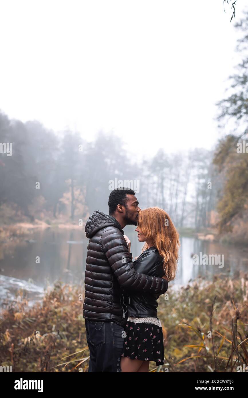 Interracial couple posing in autumn leaves background, black man and white redhead woman Stock Photo