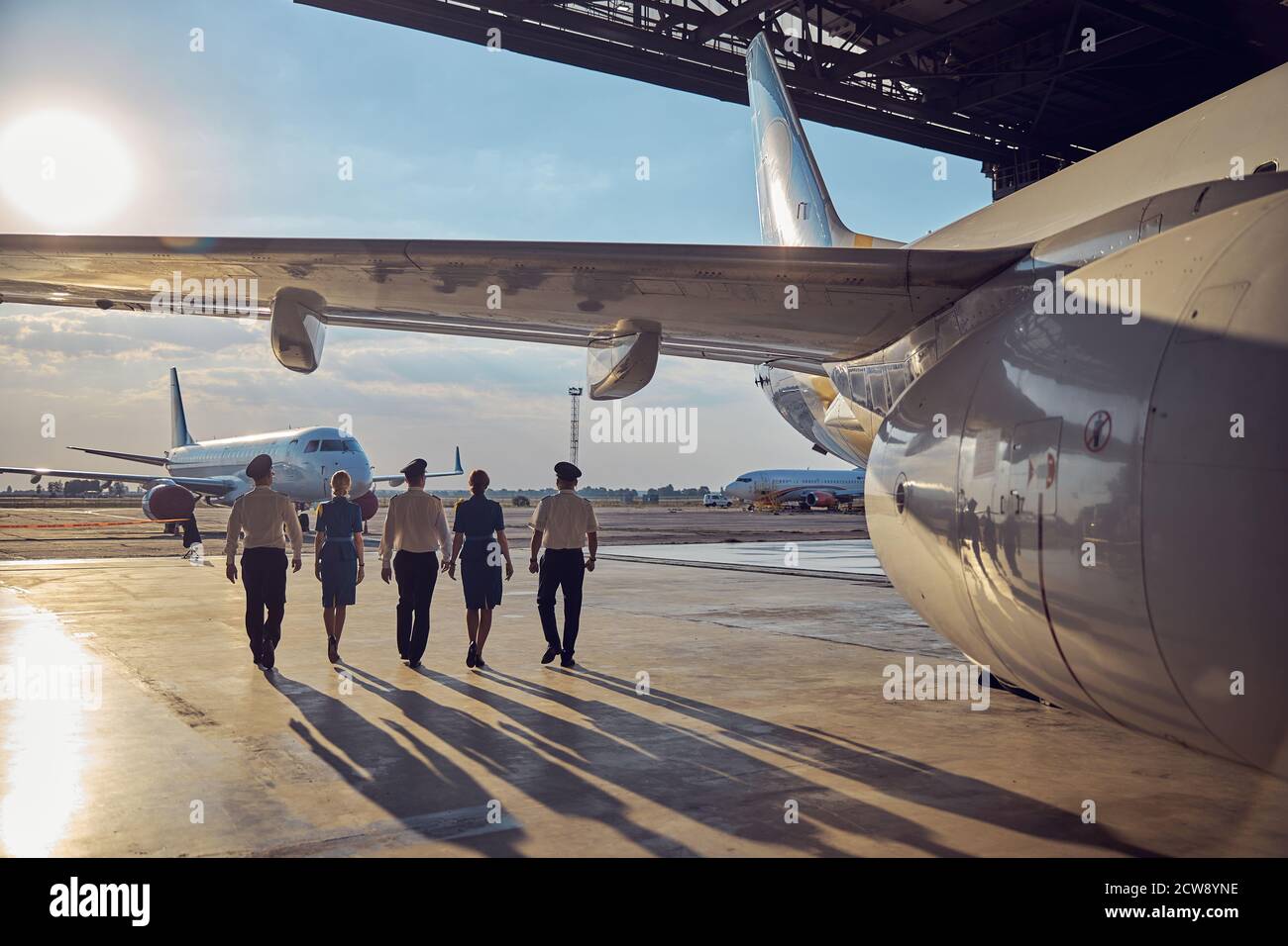 View of flight staff in the airport isolated on the sun and aircraft