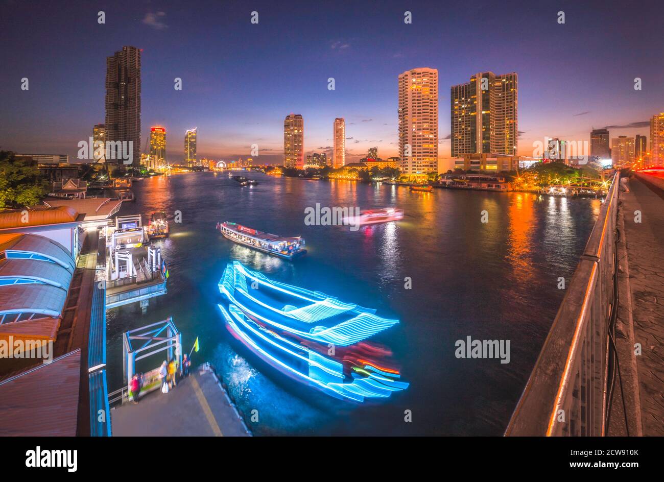 Skyscrapers and Light Trails of Traffic on the Chao Phraya River in Bangkok, Thailand as Seen from Taksin Bridge at Might Stock Photo