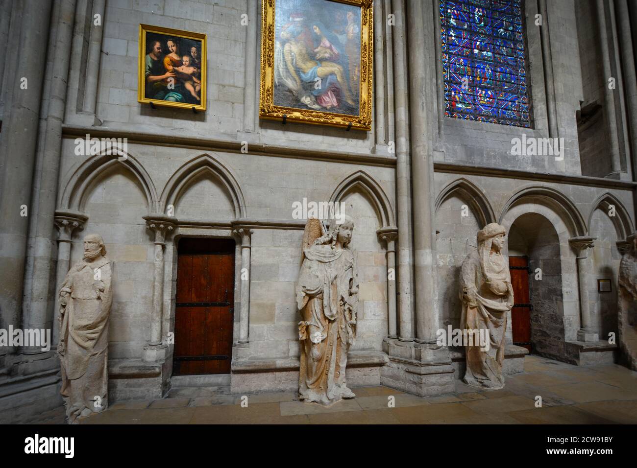 The ambulatory of the interior of the Rouen Cathedral in Rouen France with stained glass windows, statues and renaissance paintings Stock Photo