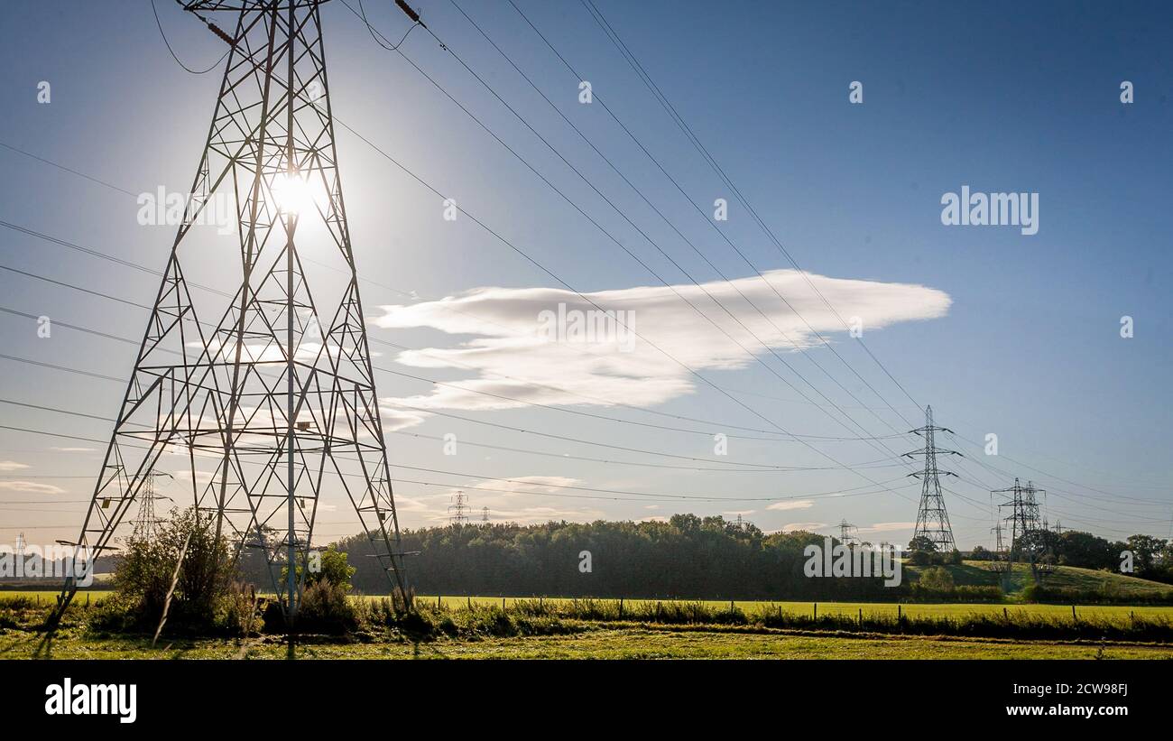 Electricity pylons in a rural setting with a blue sky. Stock Photo