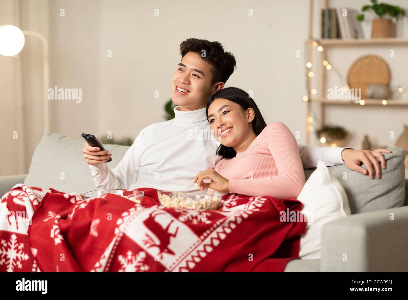 Happy Chinese Couple Watching TV On Christmas Eve At Home Stock Photo