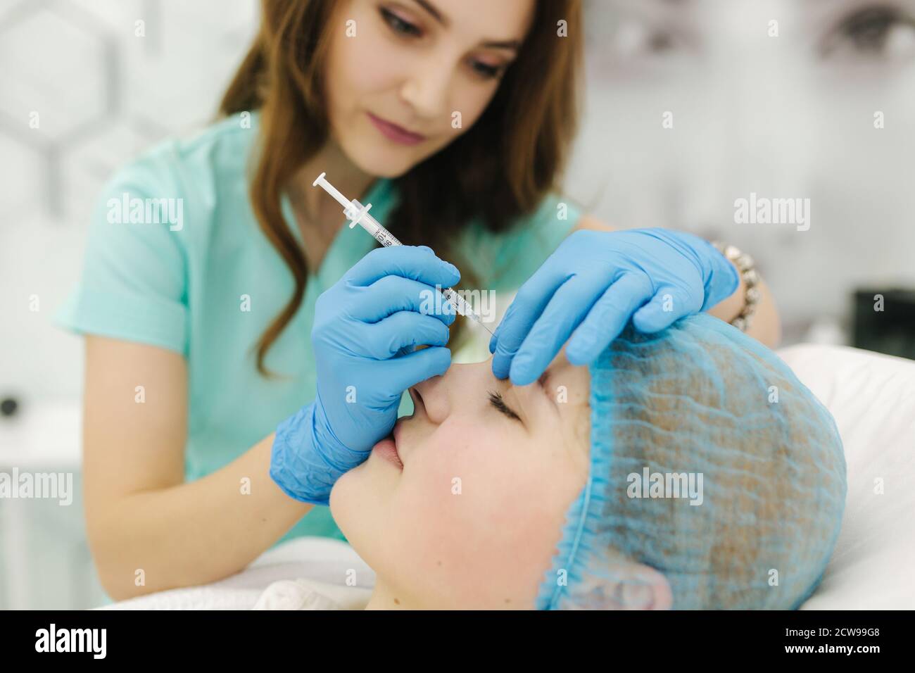 Person Getting Face Injection Hands of cosmetologist making injection in face, lips. Young woman gets ...
