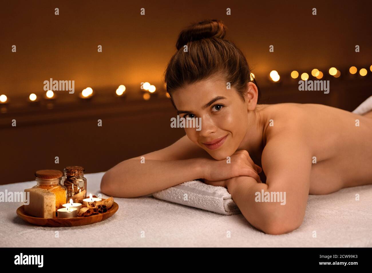 Smiling lady laying on massage table, enjoying aromatherapy session Stock Photo