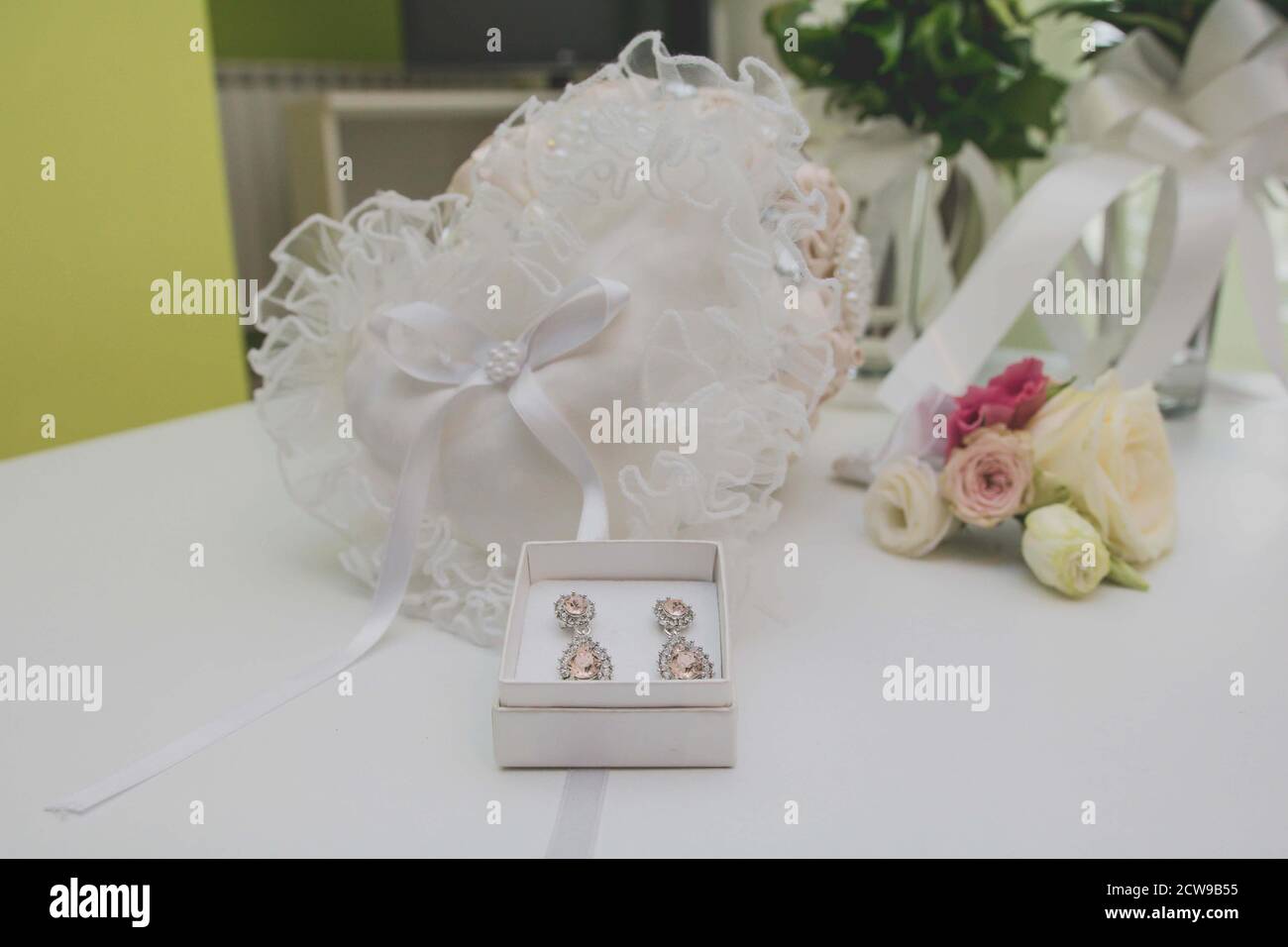 Closeup shot of beautiful diamond earrings in a box next to wedding flowers Stock Photo
