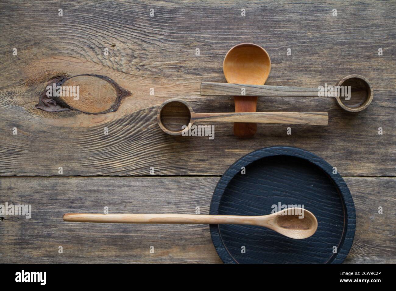 Top view wooden spoons and plates made of precious wood on wooden table, eco-friendly cutlery concept, selective focus Stock Photo