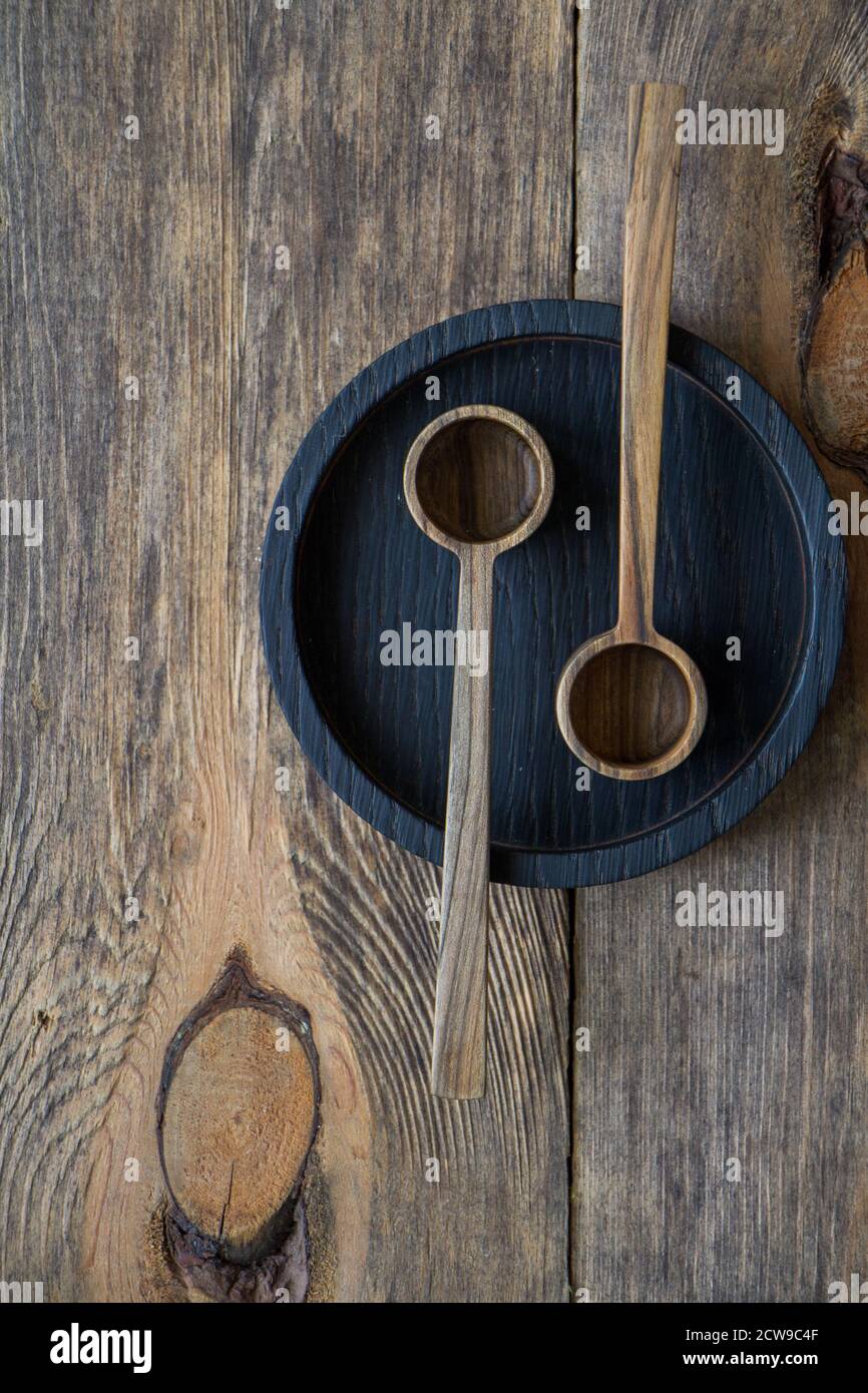 Top view two wooden spoons on black plate on wooden table, eco-friendly cutlery concept, selective focus Stock Photo