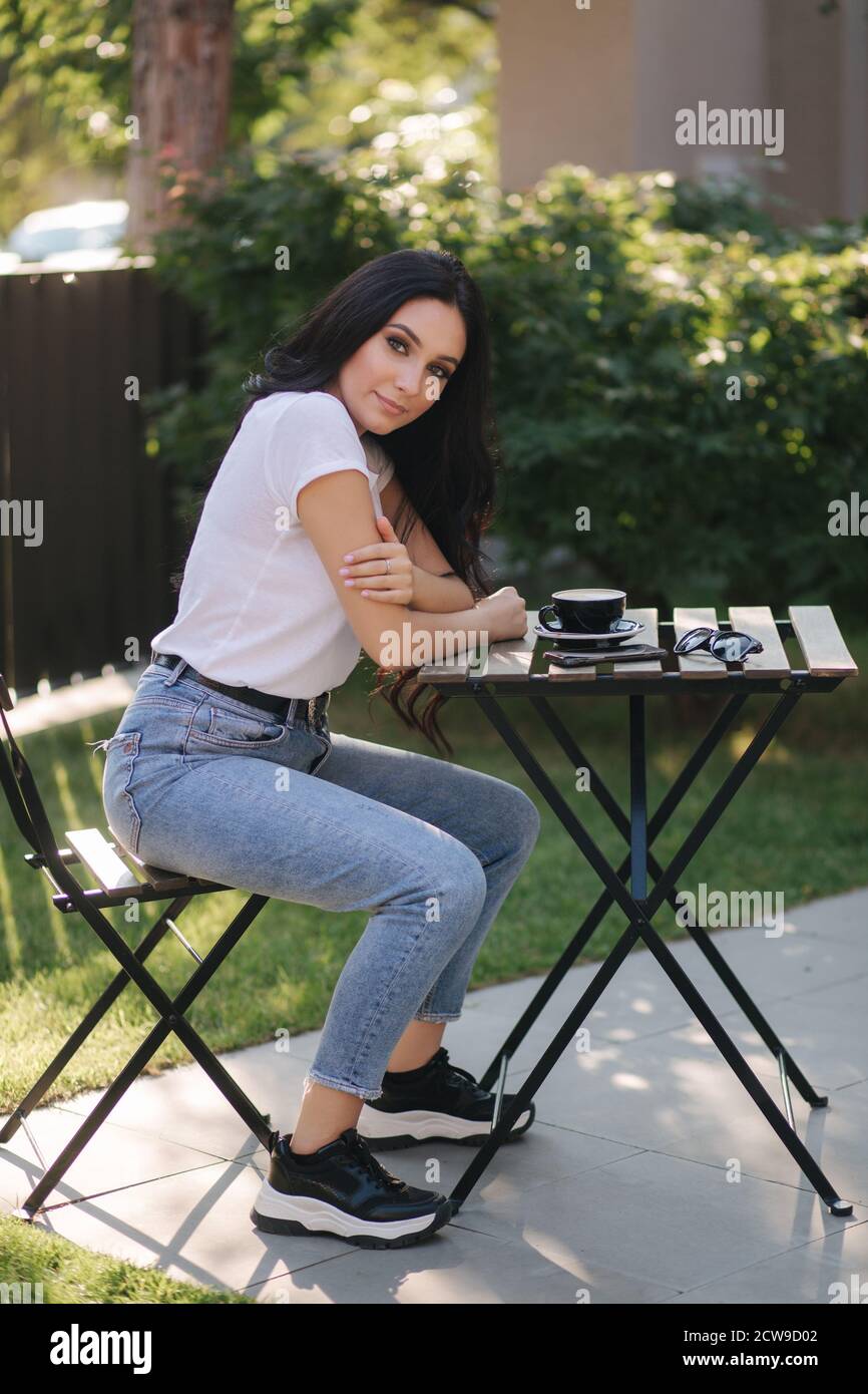 Attractive young woman sitting in caf outdoors and drink coffee Stock ...
