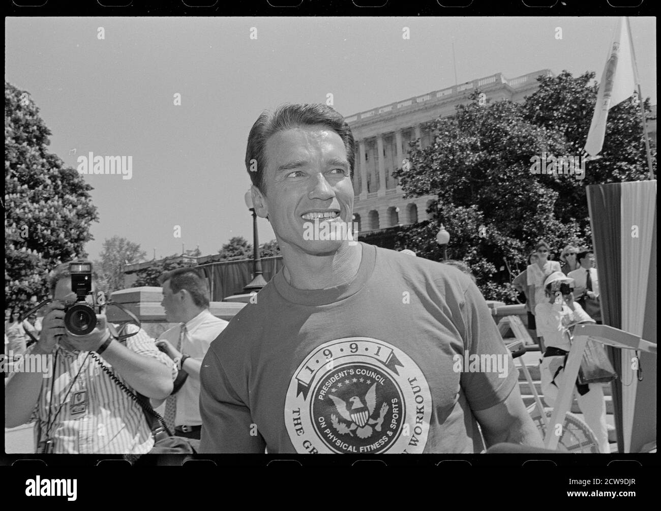 Arnold Schwarzenegger pumping up arms in his retro UAB t-shirt.