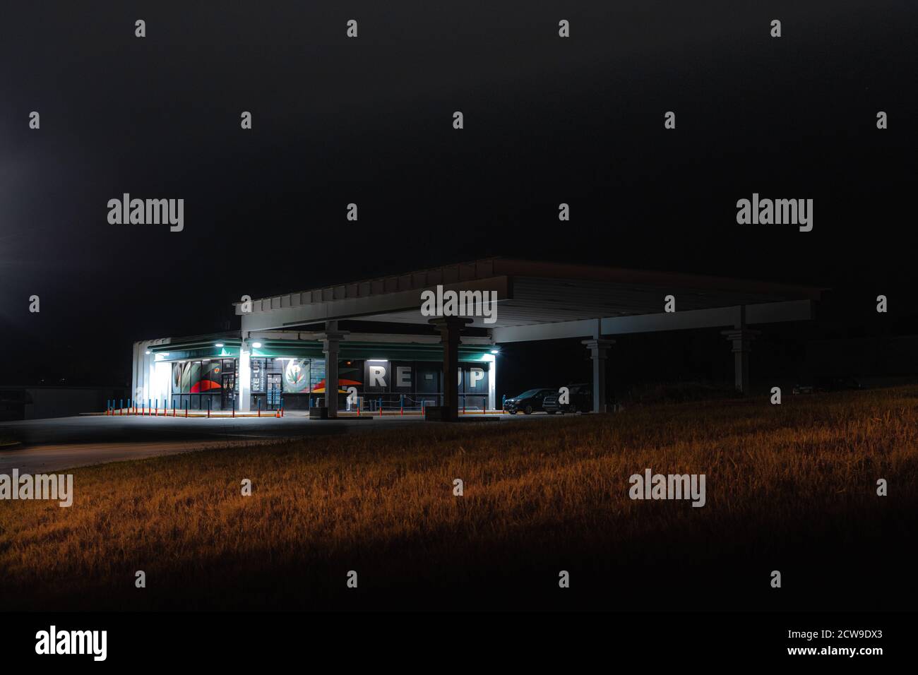 A moody abandoned/repurposed retro gas station dimly lit in the middle