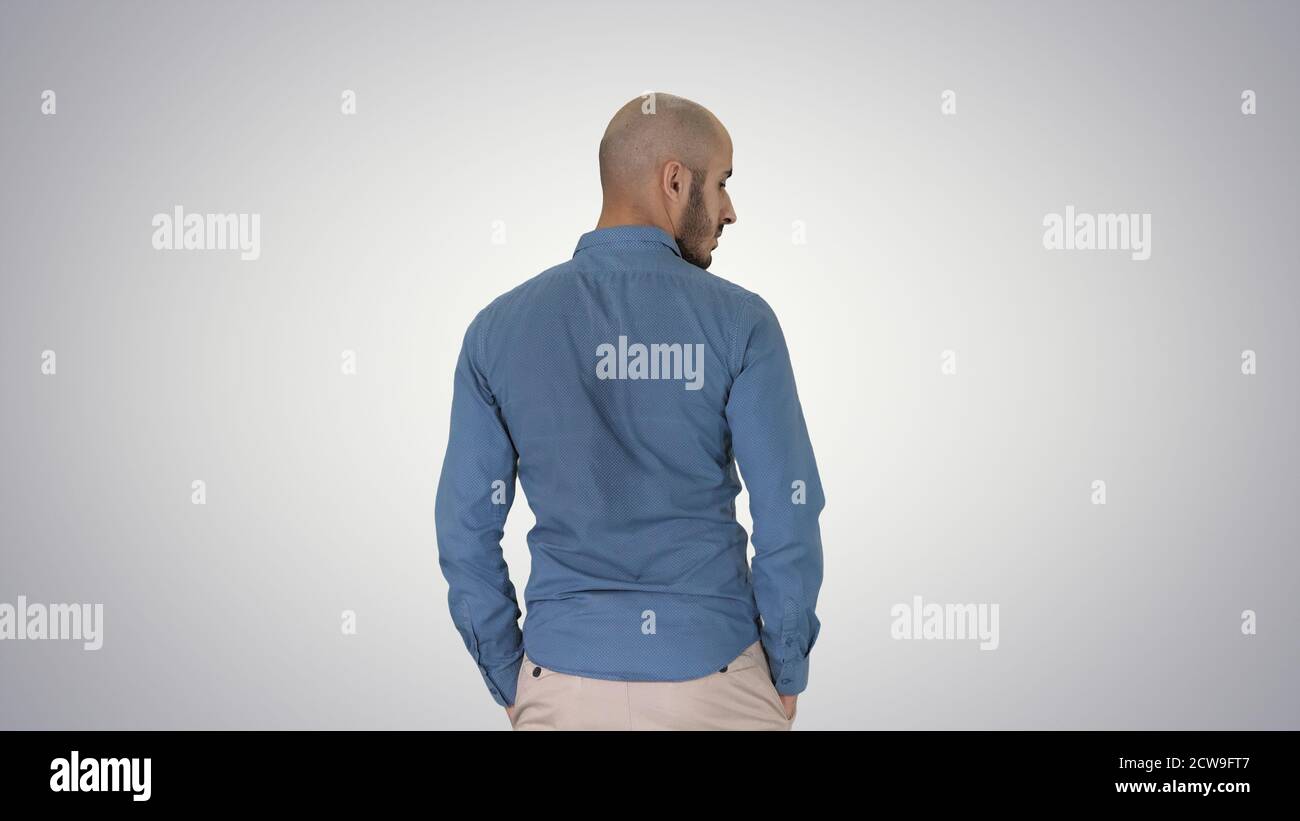Arab in casual looking around with hands in pockets on gradient Stock Photo