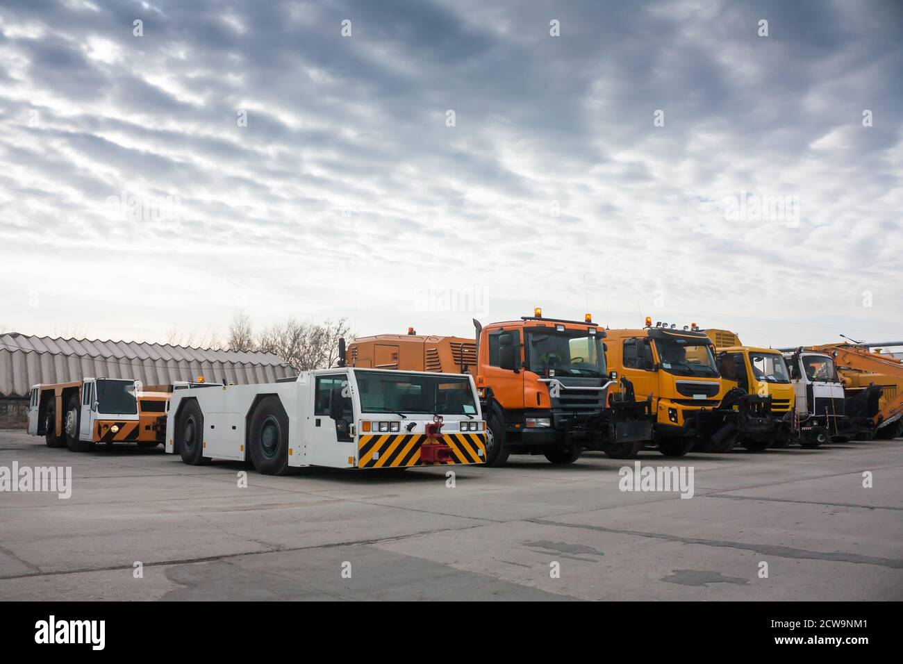 Tow tractors and cleaning trucks in the airport Stock Photo
