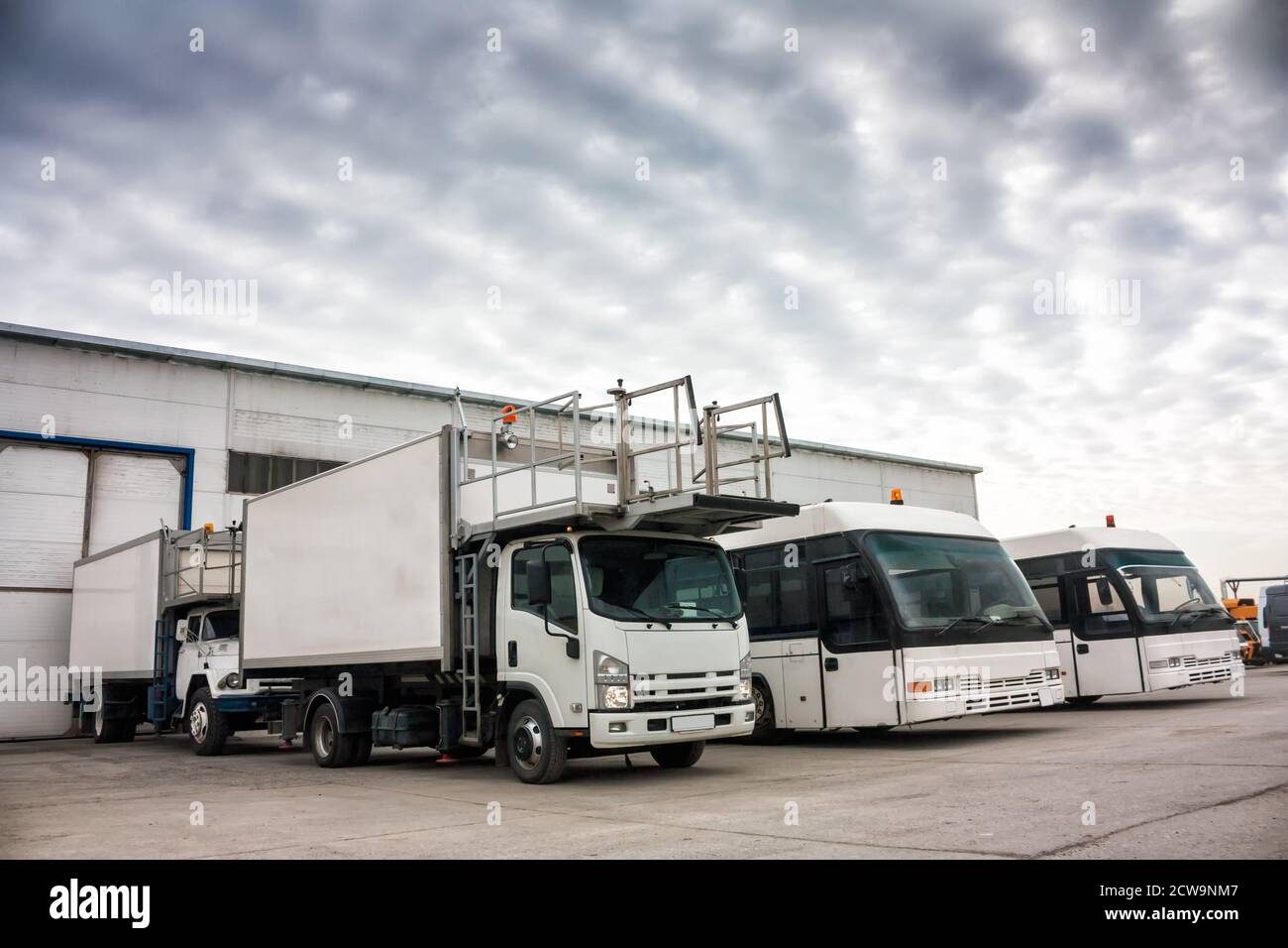 Aircraft caterers and airport buses in the parking lot near the garages Stock Photo