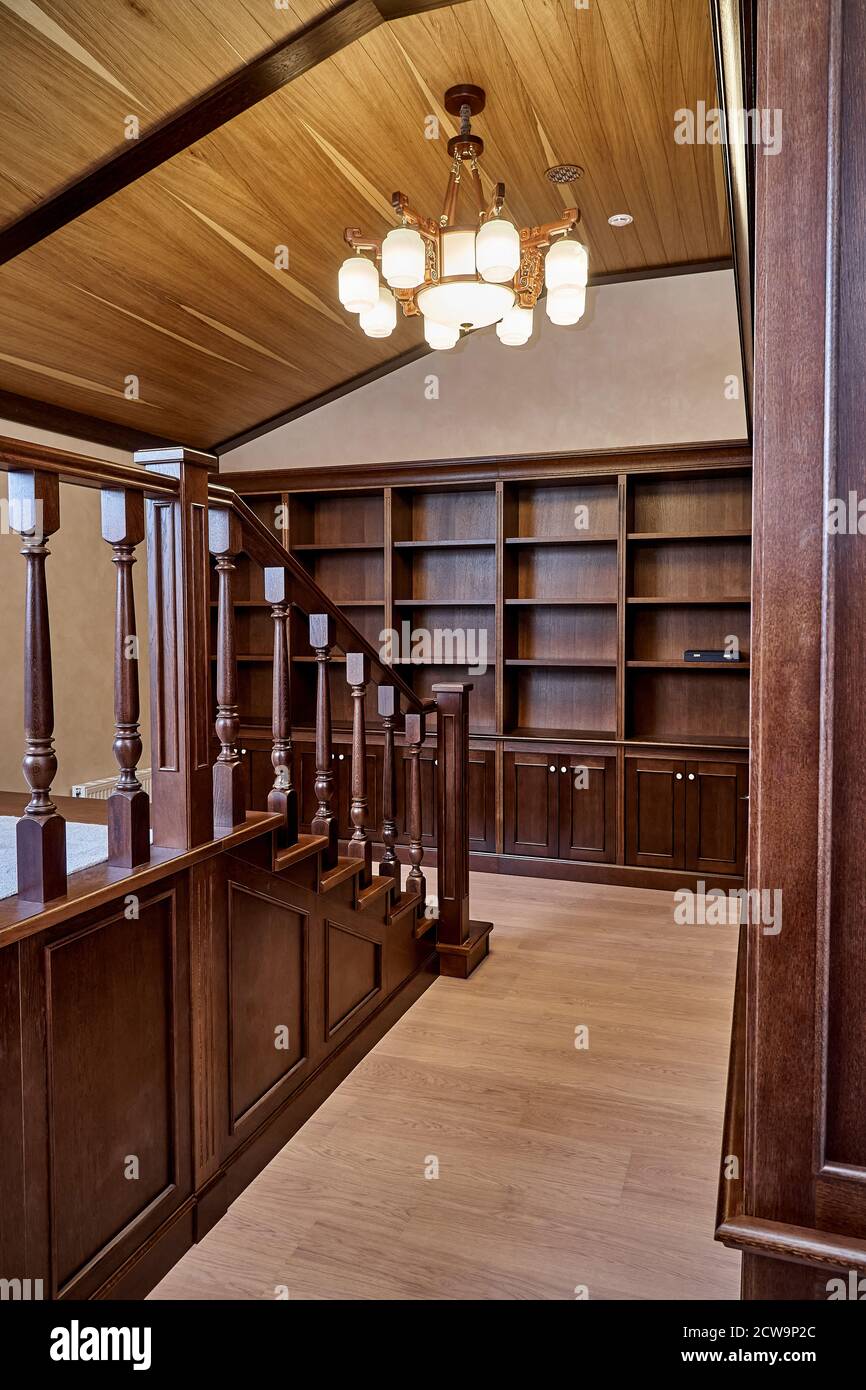 Home library. Wooden bookcase with empty shelves and a wooden balustrade placed in home library in house Stock Photo