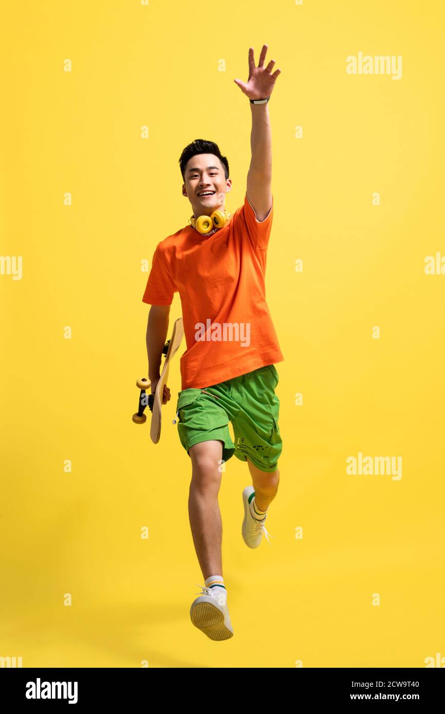 Holding a skateboard bouncing young man Stock Photo