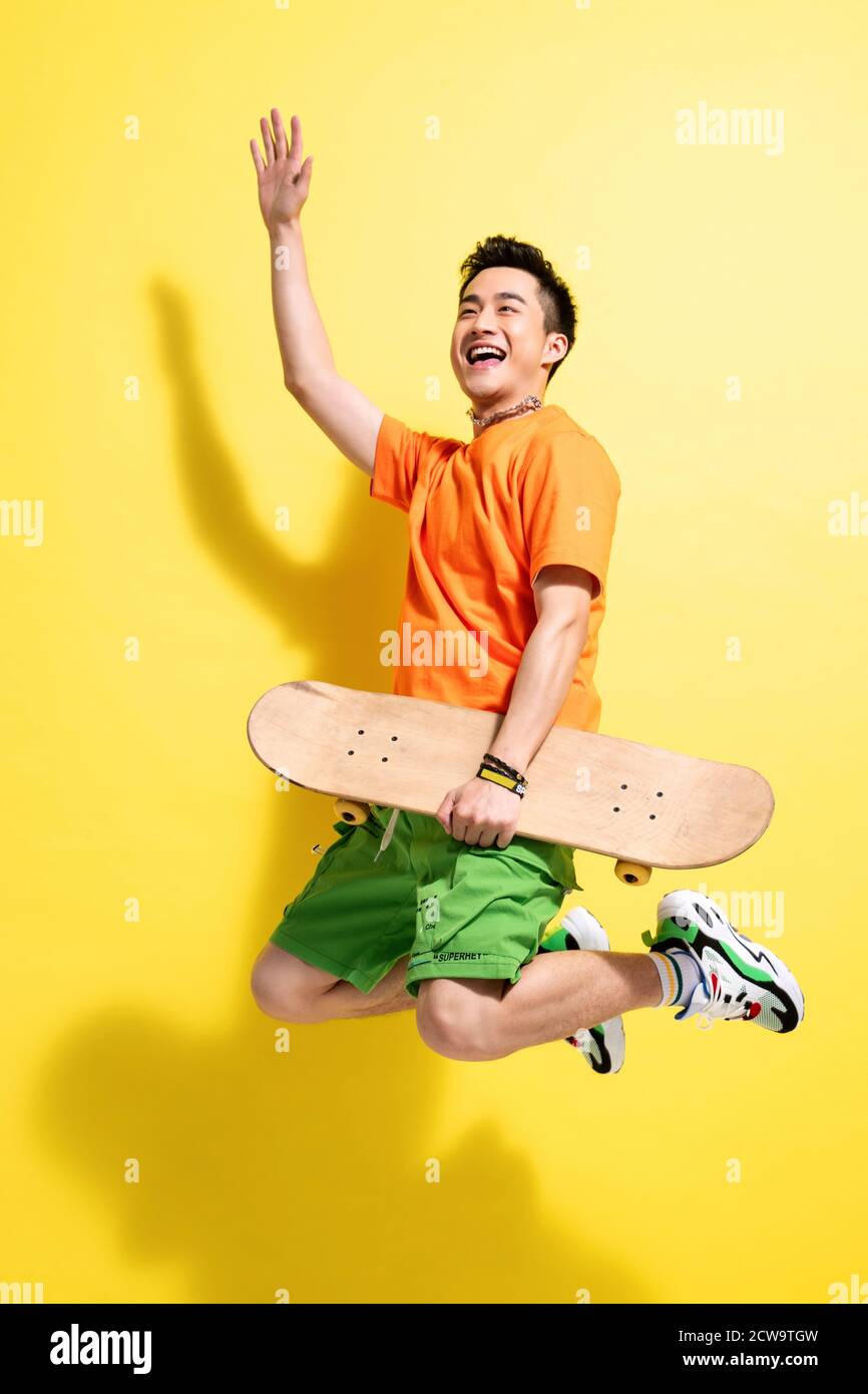 Holding a skateboard bouncing young man Stock Photo
