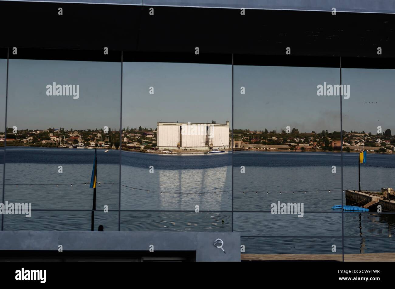Reflection in the glass facade of a modern building. A modern corporate building by the river. Reflection River and the opposite bank with an elevator Stock Photo