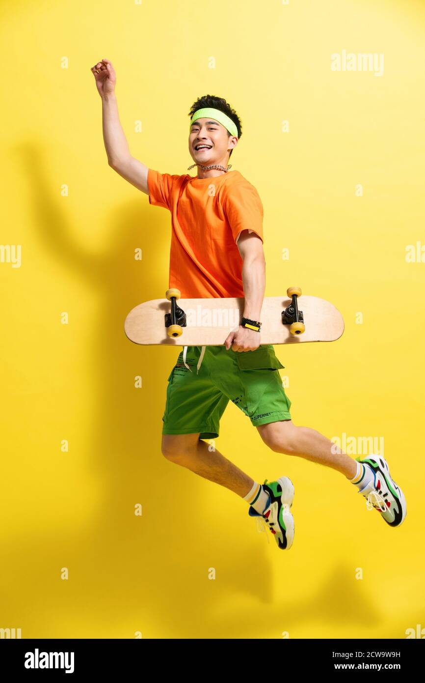 Holding a skateboard bouncing young man Stock Photo